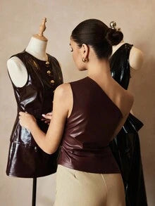 Woman wearing a chocolate brown one-shoulder faux leather blouse with diagonal draping and a fitted waist silhouette.