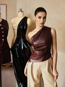 Front view of a chocolate brown asymmetric faux leather top styled with cream trousers for an elegant evening outfit.