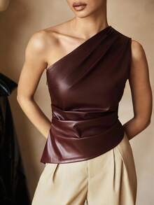 Rear view of a woman wearing a chocolate brown one-shoulder faux leather top with a fitted waist and asymmetric neckline.