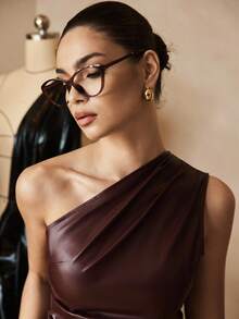 Close-up of a chocolate brown faux leather top showing an elegant one-shoulder neckline and softly draped front detailing.