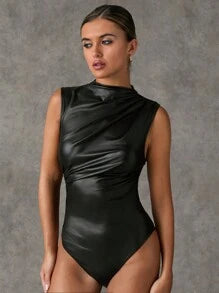 Angled view of a black sleeveless leather-look bodysuit styled with dark jeans, showing a high neckline, diagonal draping and fitted waist.