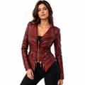 A woman modeling a burgundy faux leather moto jacket with gold-tone hardware and studded details on the shoulders, paired with black pants against a plain white background.