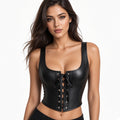 A woman modeling a black faux-leather corset-style top with a scoop neckline, wide shoulder straps, and front lace-up detailing with silver eyelets, against a plain white background.