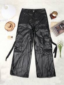 Black glossy cargo pants laid flat on a light beige surface, surrounded by small styled props including a hat, glasses, a book, and a small flower sprig.