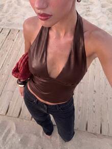 Burgundy faux leather halter crop top with wide neck straps, a deep V-neckline and smooth fitted waist panel, styled with black jeans.