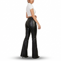 A woman shown from the back wearing black flared faux-leather pants and a white short-sleeve crop top against a plain white studio background.